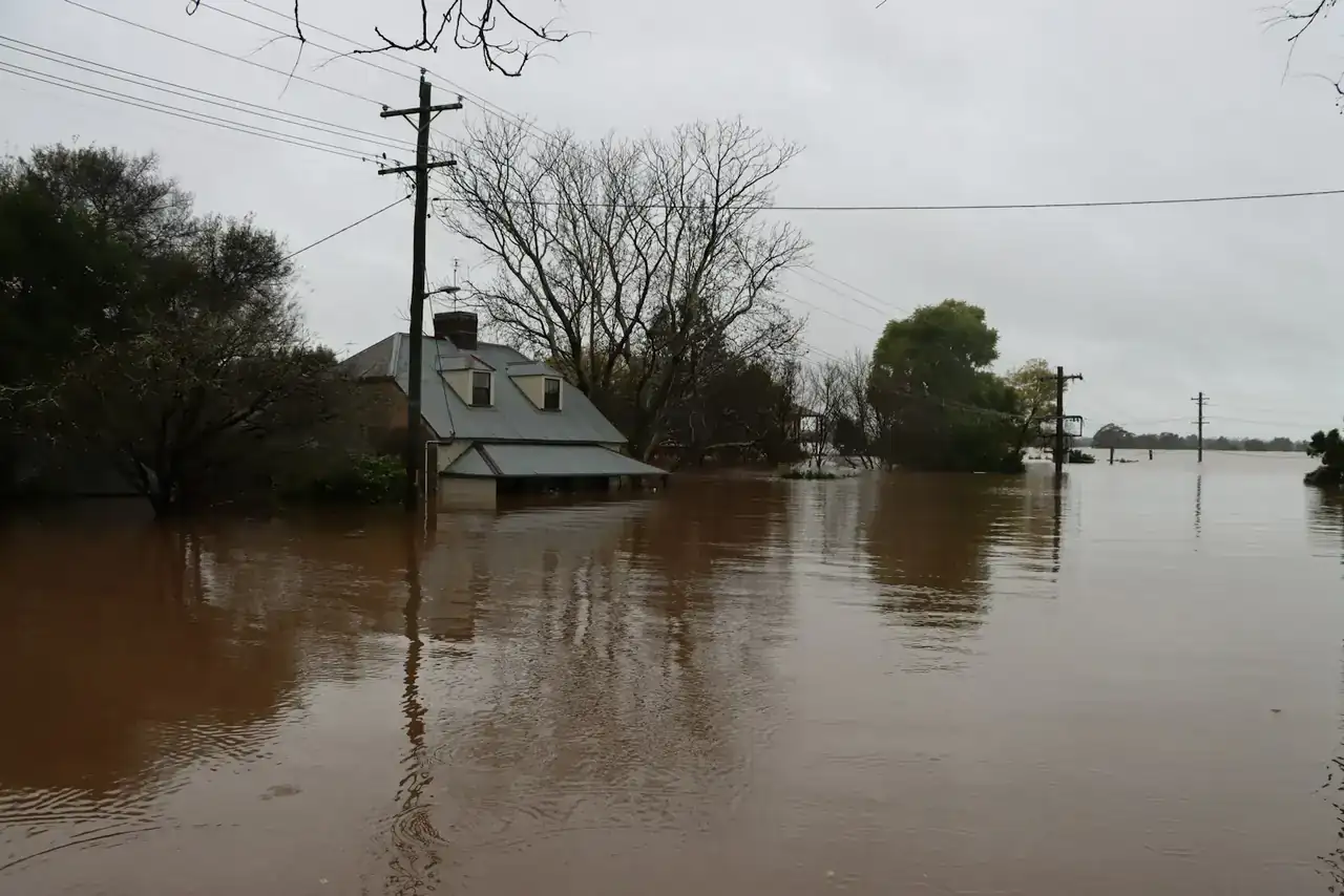 Floodwater covering a street and yards around a house