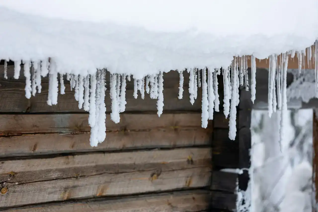 Long icicles hanging from a snowy roof edge