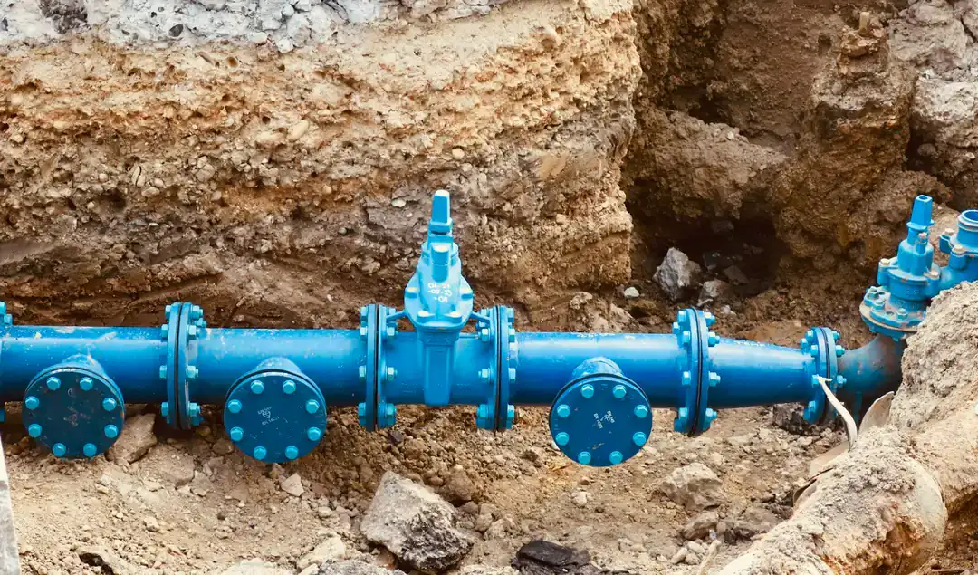 Water main pipe and valves exposed in an excavated trench