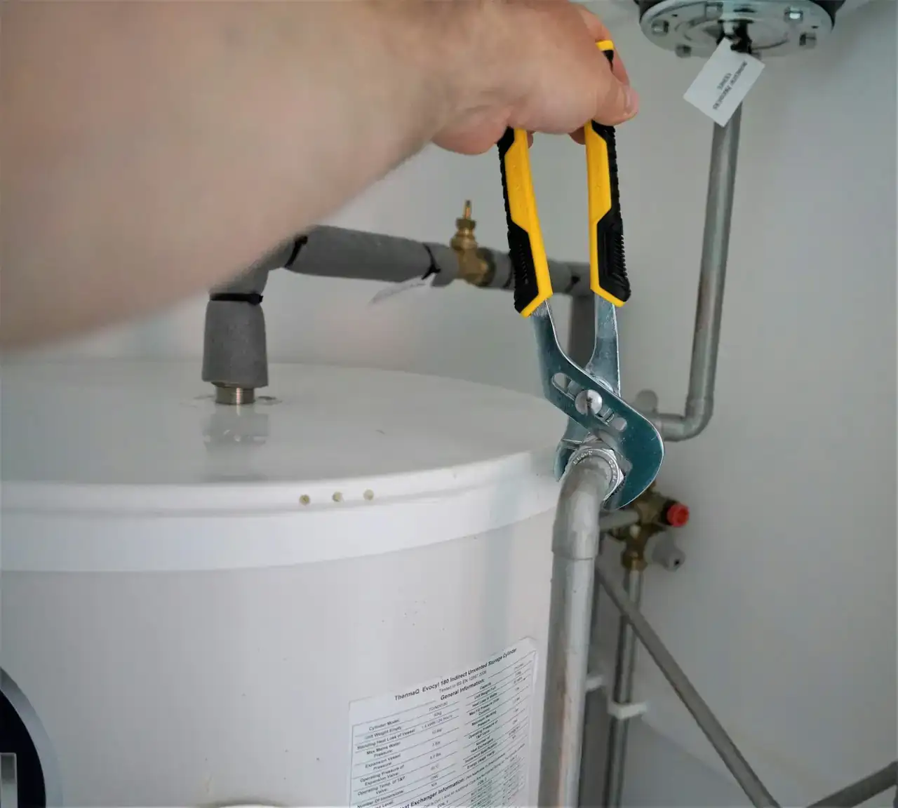 Plumber using pliers on a water heater connection